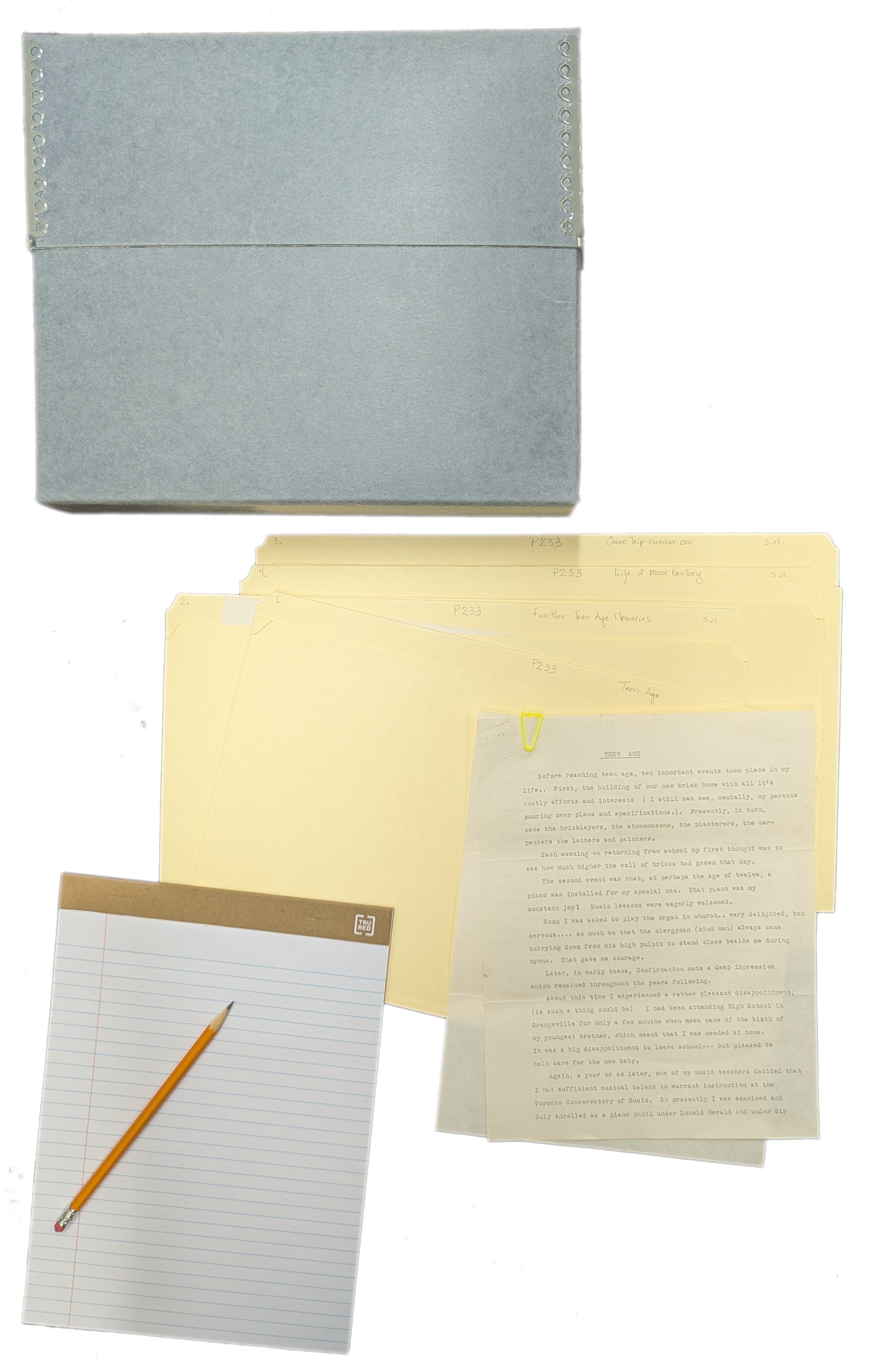 archival storage box, archival files, a typed document, pad of paper and pencil