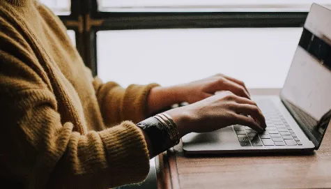 two hands positioned over the keyboard of a laptop