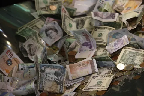 A photo of the British Museum's donations box, including bills and coins from many different countries.