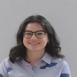 Headshot of Amelia Ritchie. She is a white woman with shoulder length brown hair, a round face, and glasses. She is wearing a purple blouse.