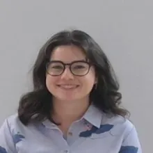 Headshot of Amelia Ritchie. She is a white woman with shoulder length brown hair, a round face, and glasses. She is wearing a purple blouse.