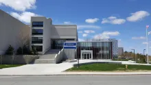 Alphonse Raymond building, north side, featuring a large concrete facade and steps next to a glass section with an entrance at ground level